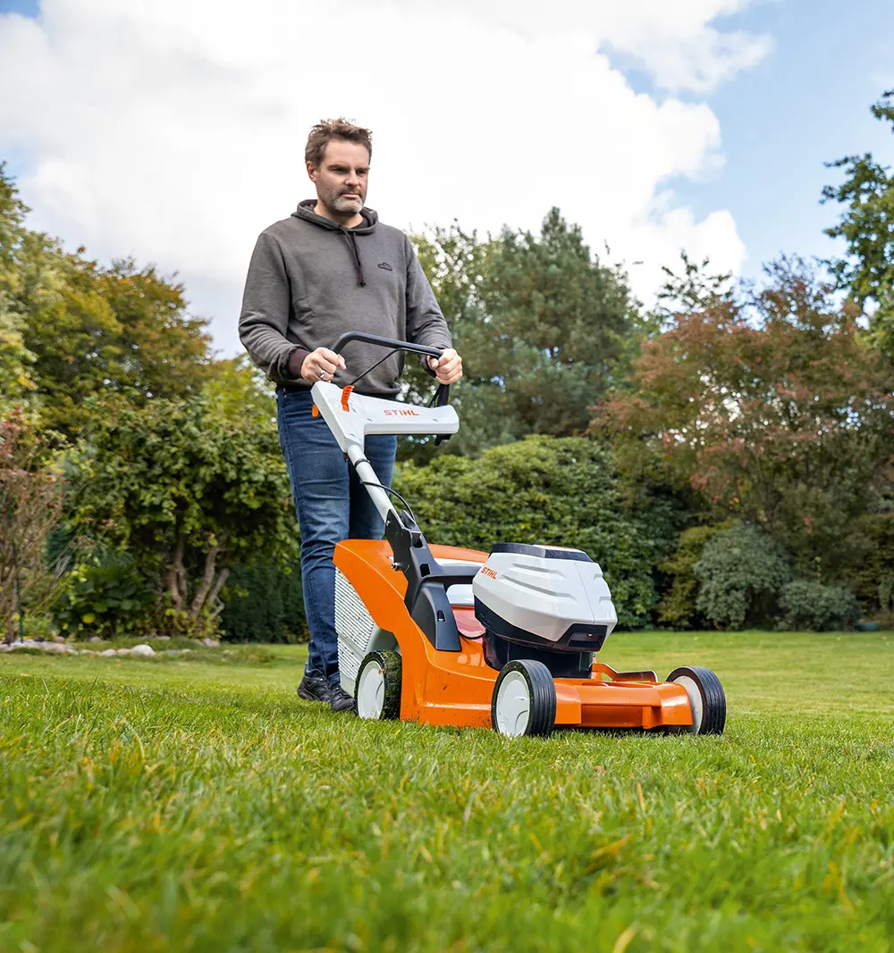 A man mowing the lawn with a Stihl mower